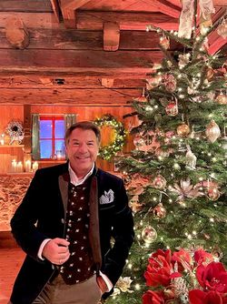 Singer Patrick Lindner stands in front of a decorated Christmas tree in a festive mood.