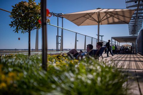 Menschen entspannen sich auf Liegestühlen auf der Besucherterrasse des Frankfurter Flughafens