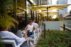Person sitzt auf einer Terrasse und genießt ein Getränk.