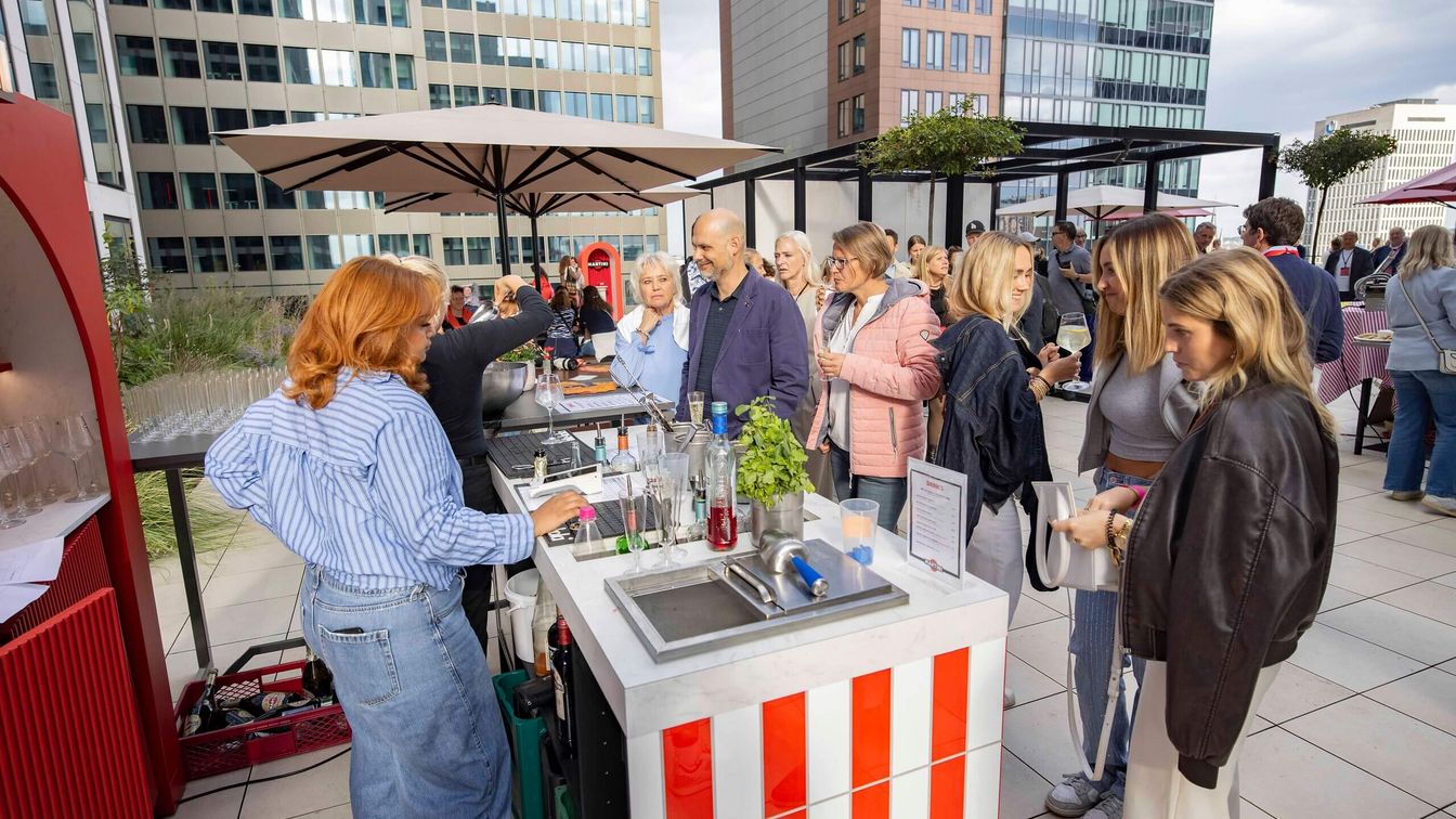 Menschen genießen Getränke bei einer Rooftop-Bar.