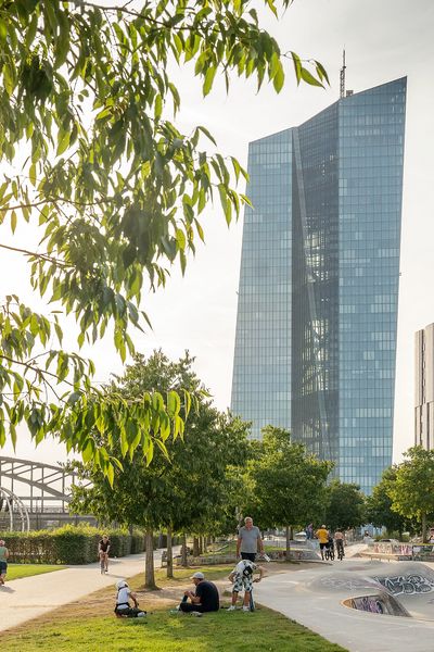 Blick auf den Hafenpark in Frankfurt mit Skatepark, Bäumen und der Europäischen Zentralbank im Hintergrund, bei sonnigem Wetter und lebendigem Treiben.