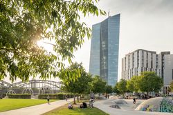 View of the harbour park in Frankfurt with skate park, trees and the European Central Bank in the background, in sunny weather and lively activity.