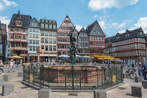 Justitiabrunnen on the Römerberg with people and the half-timbered houses of the east row