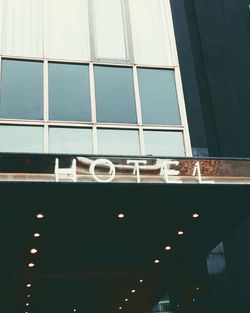Leuchtschrift „HOTEL“ an modernem Gebäude mit großen Fenstern.