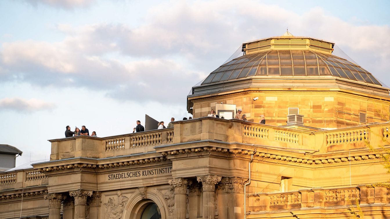 Menschen auf der Terrasse des Städel Museums beim Sonnenuntergang.