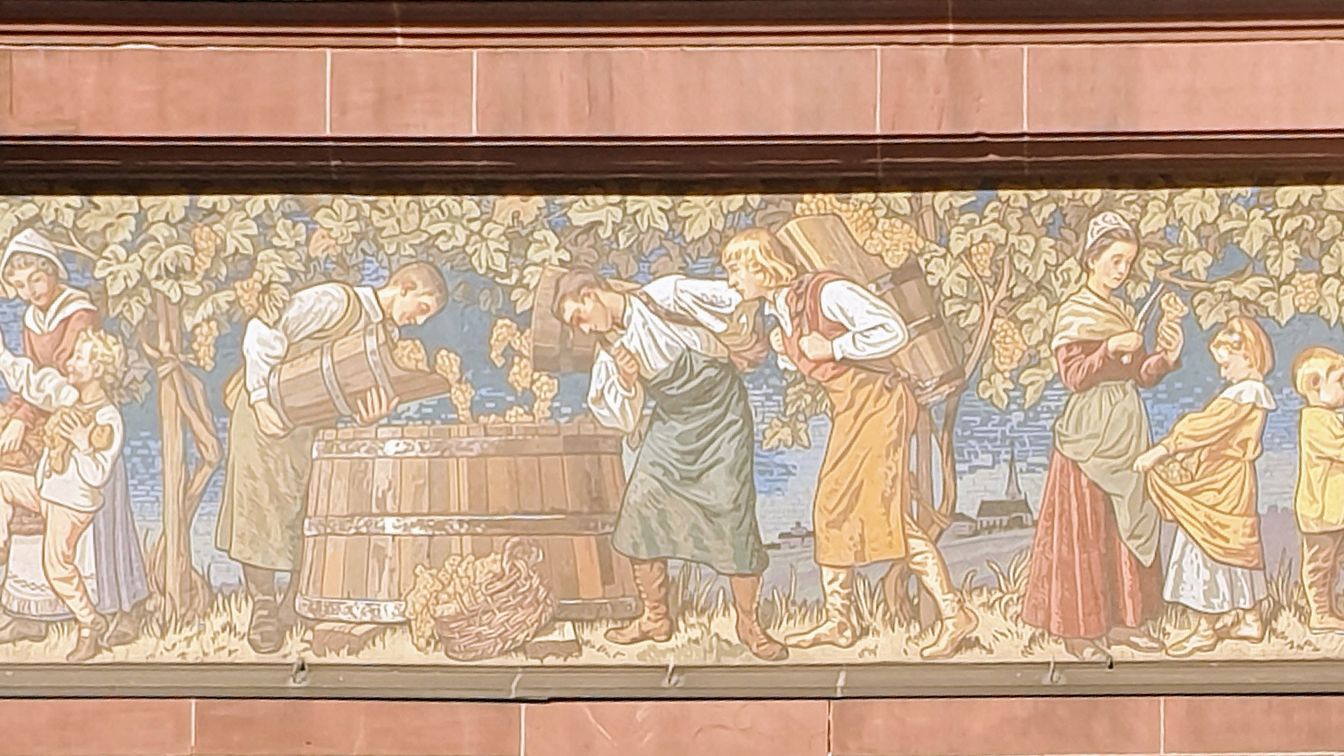 Wandfresko zeigt Weinlese mit Personen und Trauben in historischem Stil.