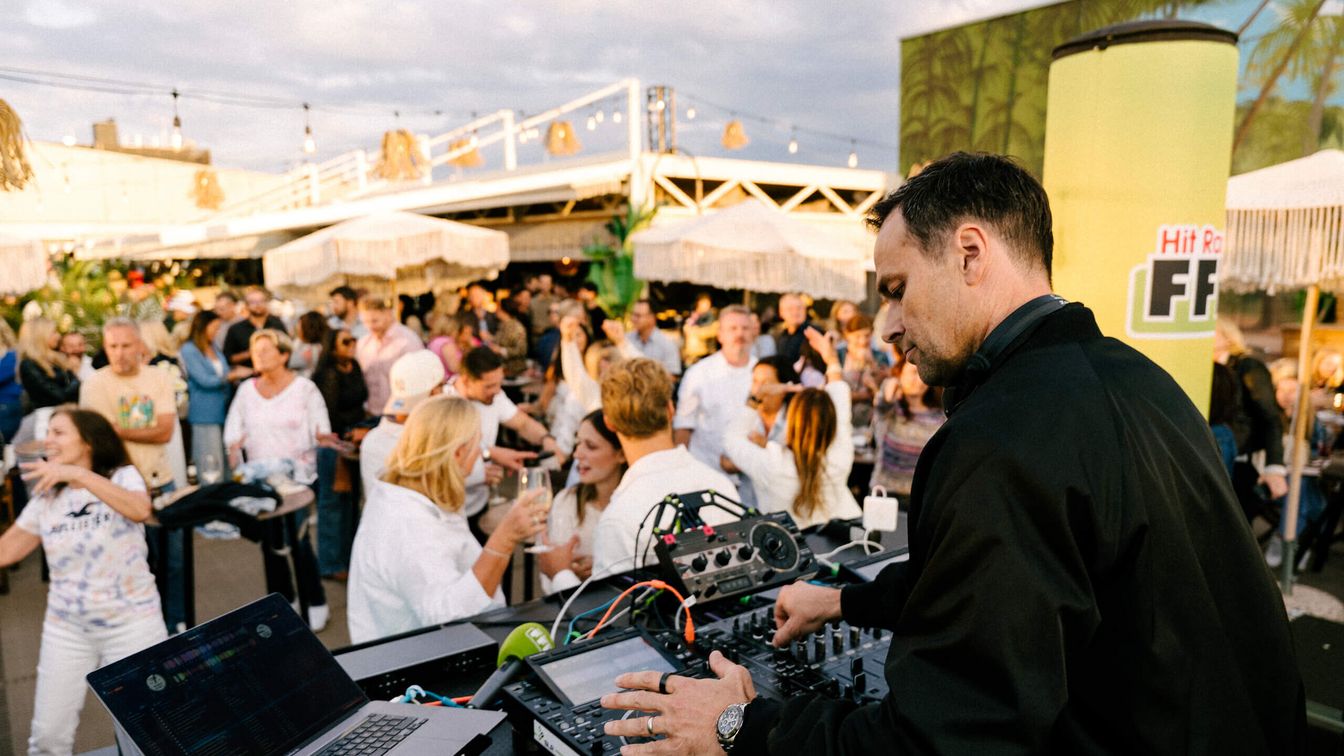 DJ legt Musik auf einer belebten Party auf der Dachterrasse auf.