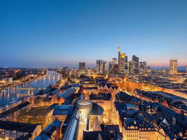 Frankfurt bei Nacht mit beleuchteter Skyline und Fluss Main.