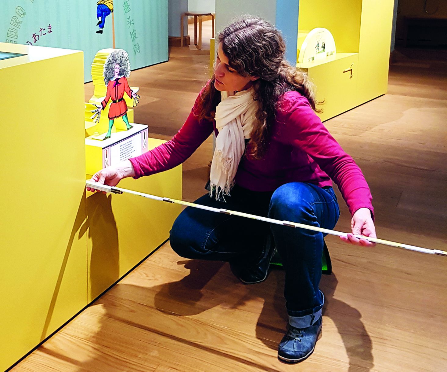 Eine Frau misst Ausstellungsstück in einem Museum mit einem Zollstock.