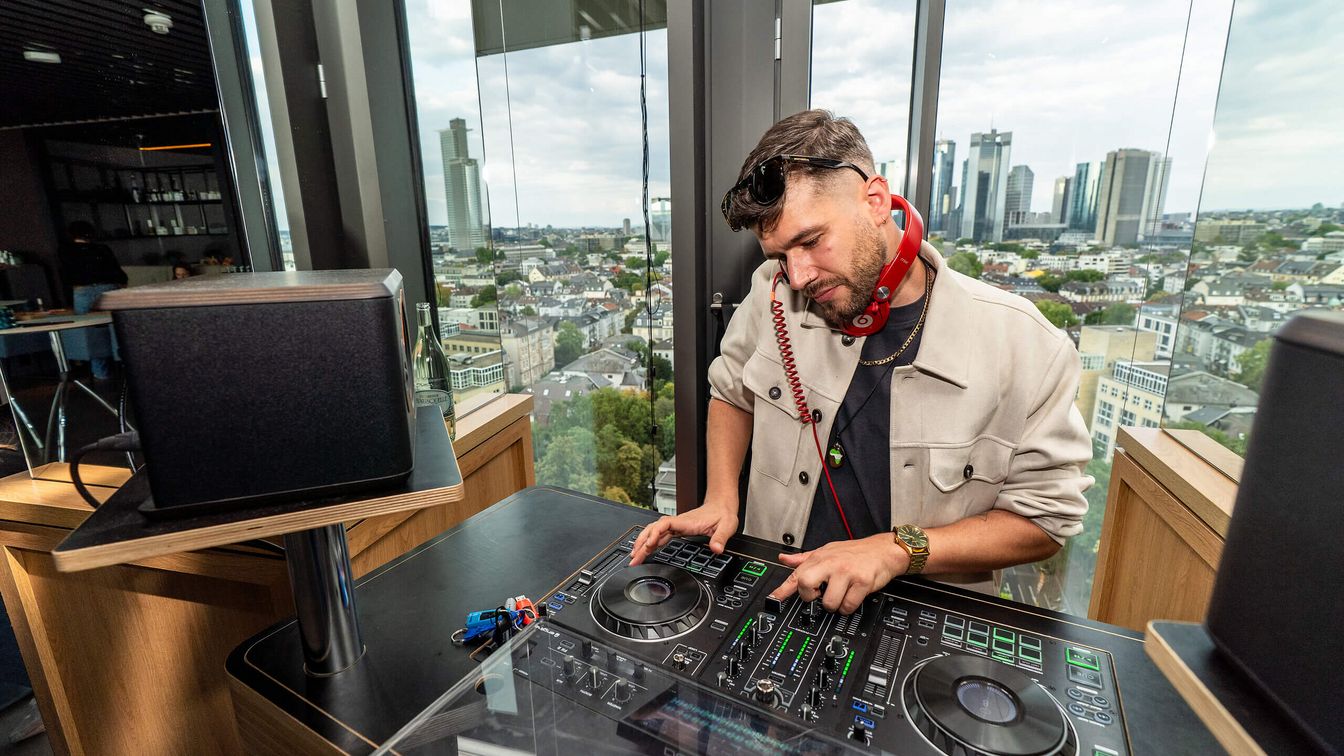 DJ legt in einer modernen Location mit Blick auf die Stadt auf.