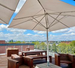 Gemütliche Lounge mit Holzmöbeln und großem Sonnenschirm auf Terrasse