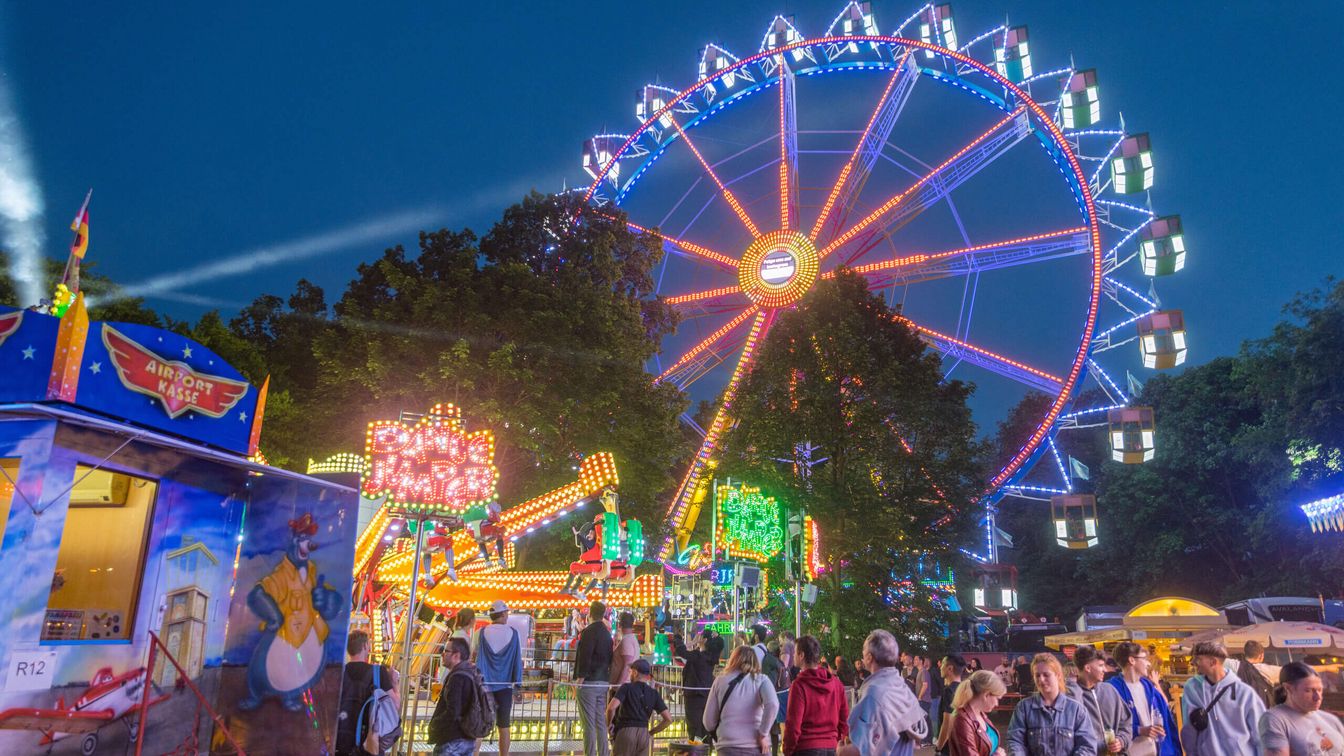 Wäldchestag visitors stroll through the festival, look at the rides and enjoy themselves 