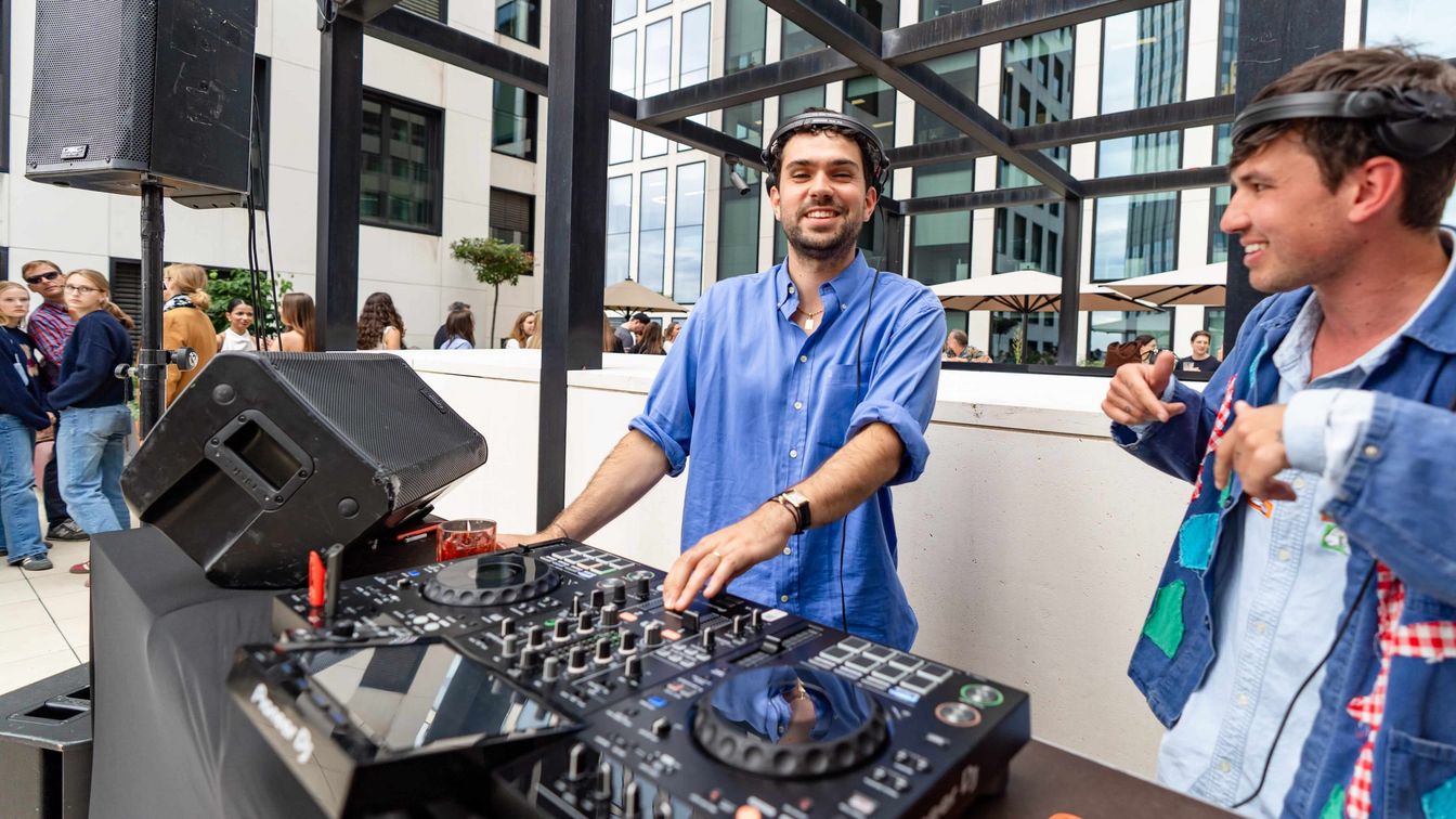DJ-Duo legt auf einer Dachterrasse in Frankfurt Musik für Gäste zwischen Hochhäusern auf.