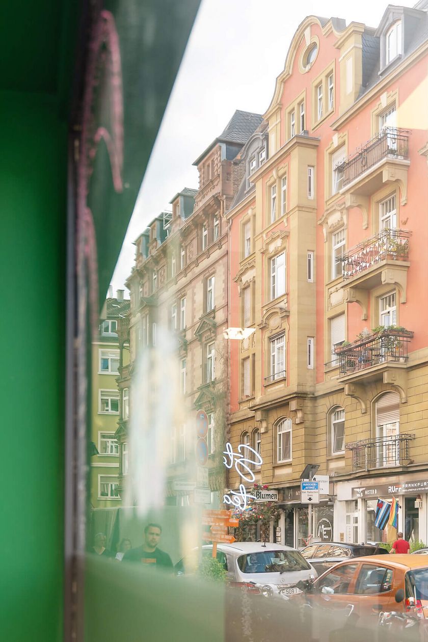 Blick auf eine belebte Frankfurter Straße mit historischen Gebäuden und Fußgänger*innen.