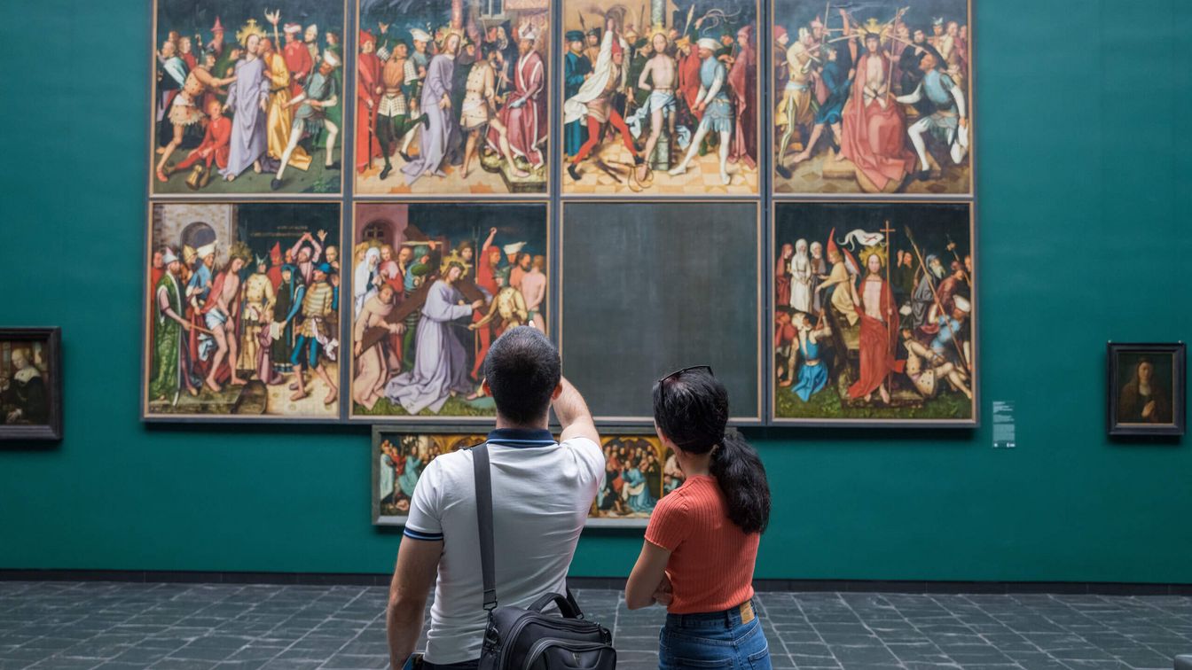 A couple admire a painting on a petrol-coloured wall. 