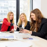 Kollegen des Presseteams sitzen an einem Tisch zusammen.