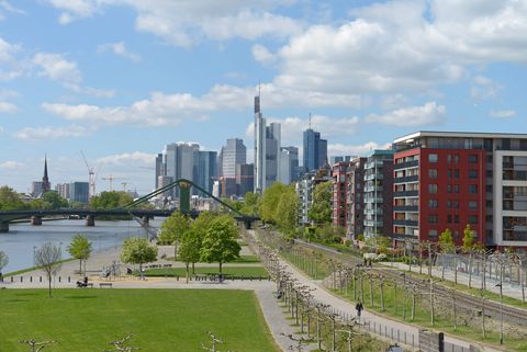 Mainufer im Frankfurter Ostend mit Blick auf Wohnhäuser, den Fluß, eine Brücke und die Skyline