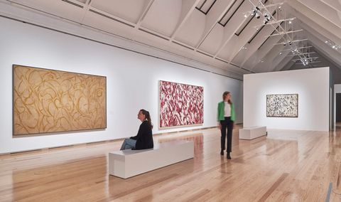 Besucher schauen sichfarbenfrohe abstrakte Gemälde in einer Ausstellung an