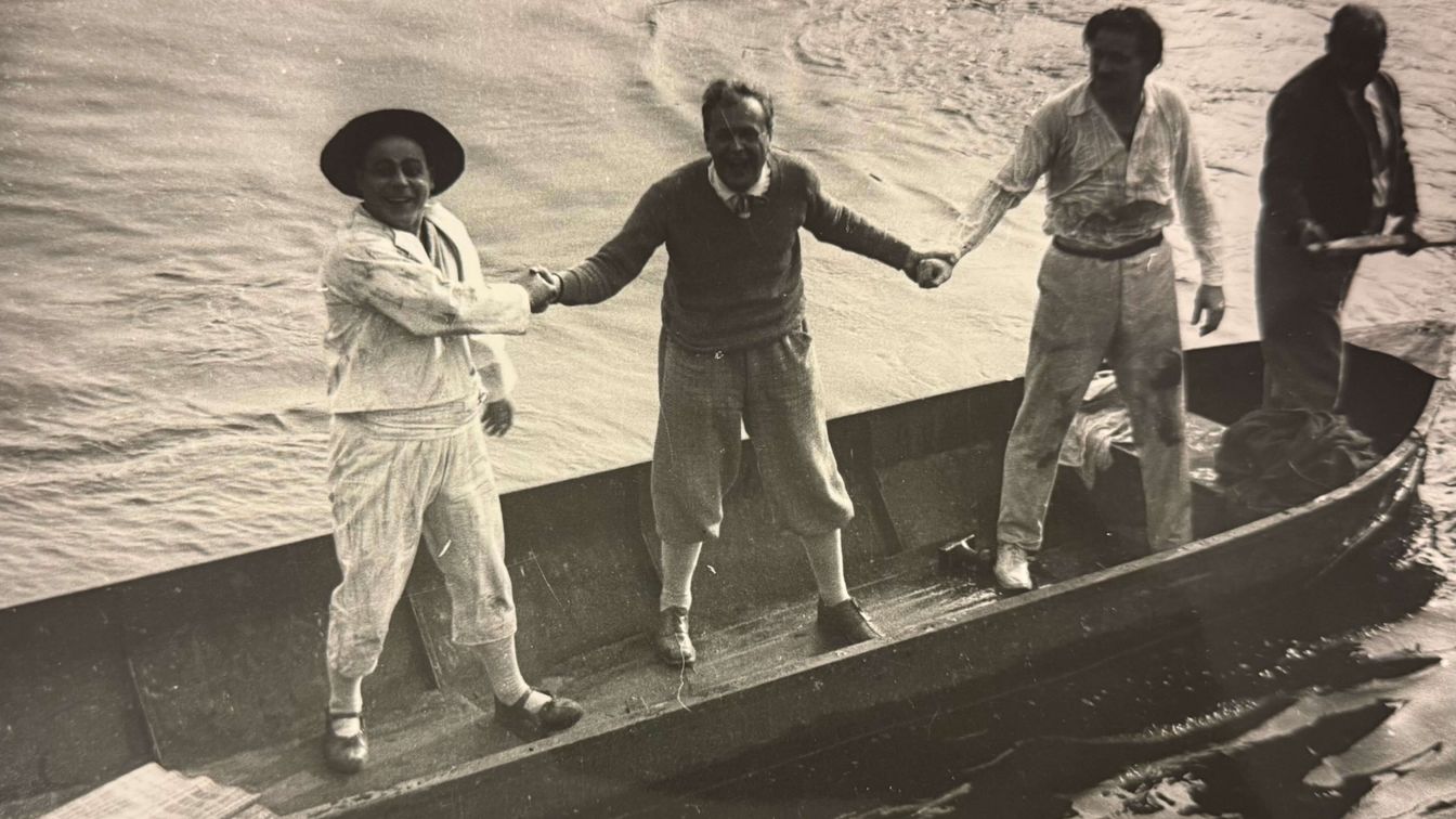 Drei Männer reichen sich die Hände in einem Ruderboot