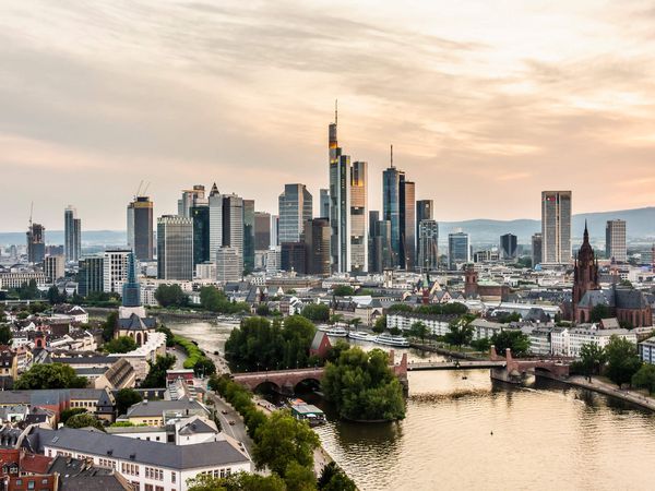 Blick auf den Main, die Frankfurter Skyline und den Kaiserdom vom Dach des Lindner Hotel Frankfurt Main Plaza bei Abenddämmerung.