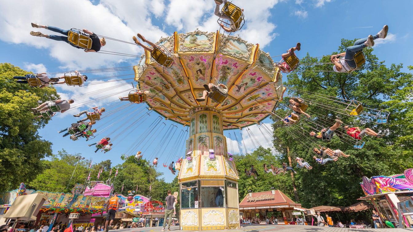 Chain carousel with happy people and in the background the forest and stalls