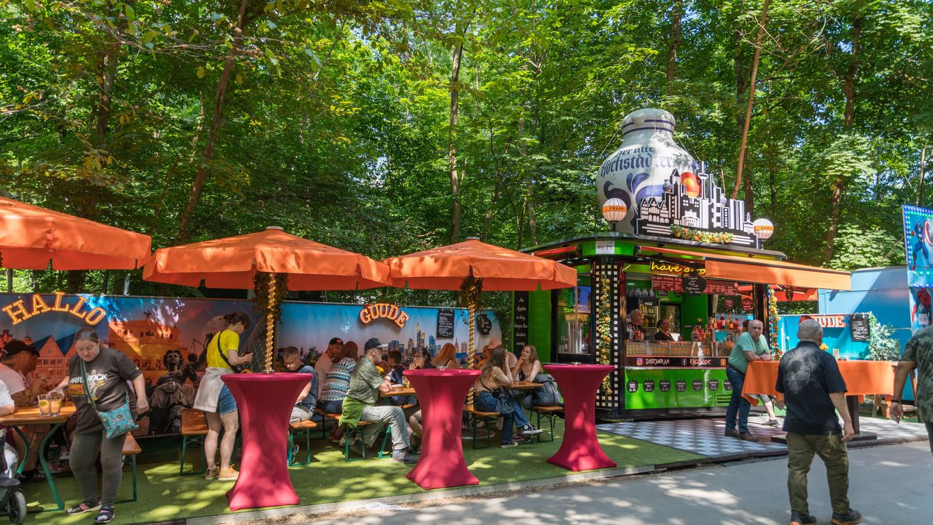 Guests sit on beer tent sets at a catering stand at Wäldchestag