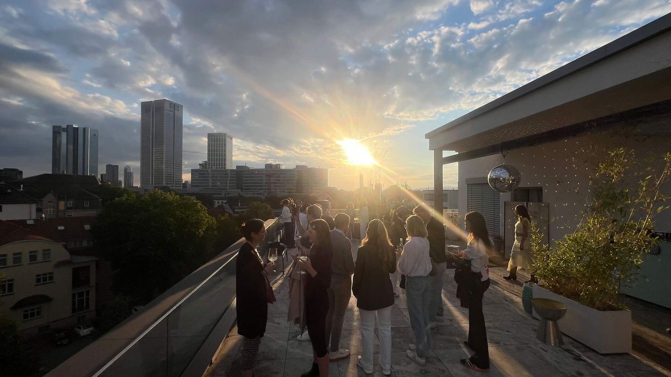 Eine Gruppe feiert während des Sonnenuntergangs auf einer Dachterrasse.