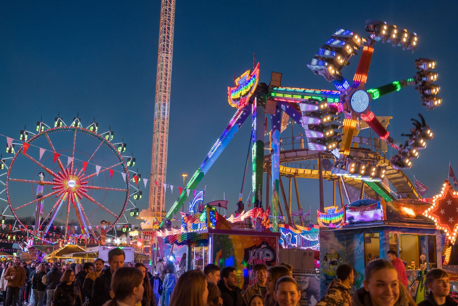 Das beleuchtete Riesenrad und Fahrgeschäfte der Dippemess