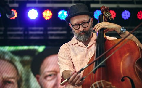 Musician playing double bass under colored lights.