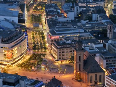 Blick über Frankfurts Innenstadt bei Dämmerung mit beleuchteten Straßen.