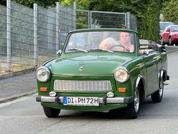 Grünes Cabrio fährt auf einer ruhigen Straße.