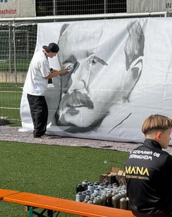 Ein Künstler gestaltet ein Bild auf einer Leinwand.