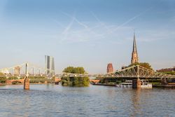 Geschwungene Eisenbrücke "Eiserner Steg" über den Main mit Dreikönigskirche im Hintergrund.