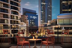 Rooftop-Bar mit roten Stühlen und Skylineblick am Abend im NH Collection Spin Tower