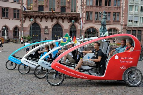 Four velotaxis in a row on the Römerberg with the Römer (Frankfurt City Hall) in the background.