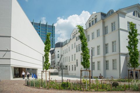 Platz mit Blumenbeet vor dem Jüdischen Museum, strahlend weiße Gebäude. Links Neubau, rechts renoviertes Rothschild-Palais.