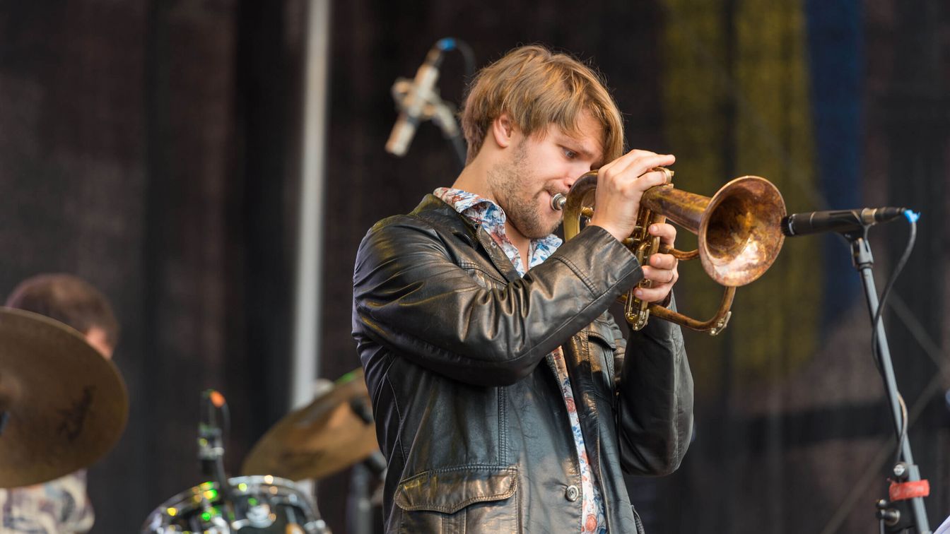 A musician plays the trumpet on a stage. 