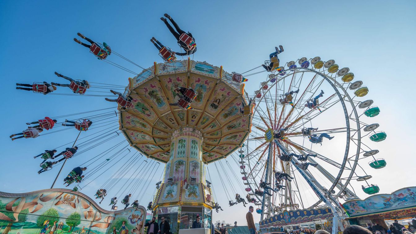 View from below the moving chain carousel and ferris wheel