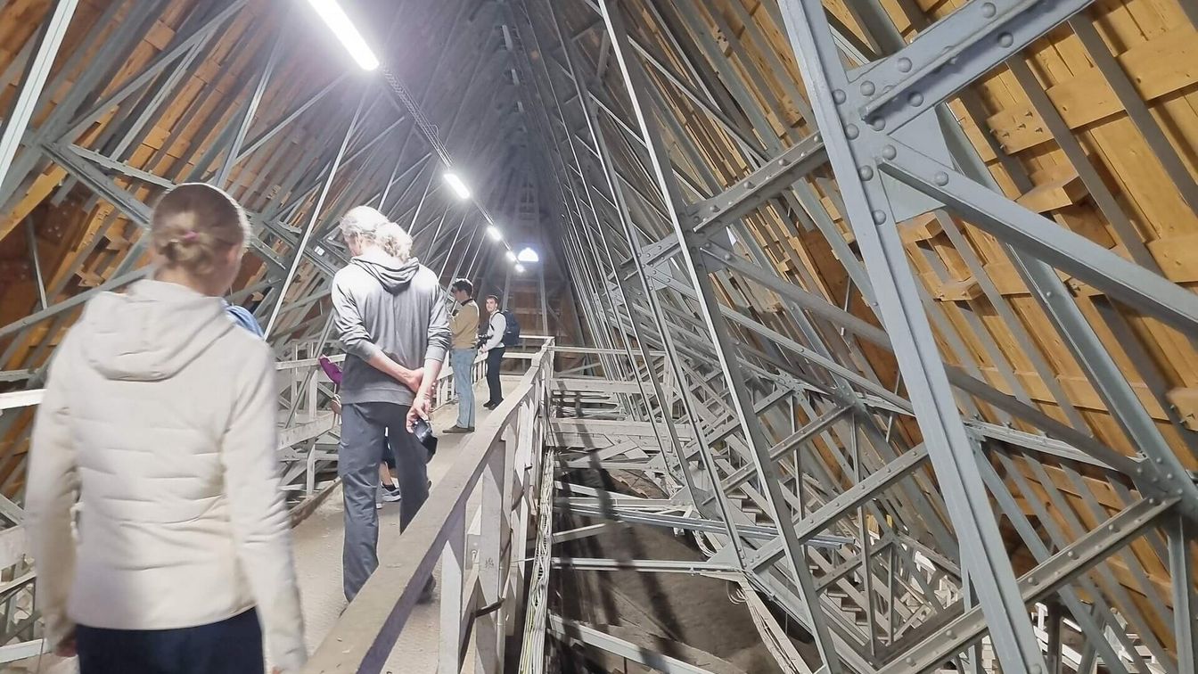 Menschen besichtigen das Innere eines historischen Dachstuhls. 