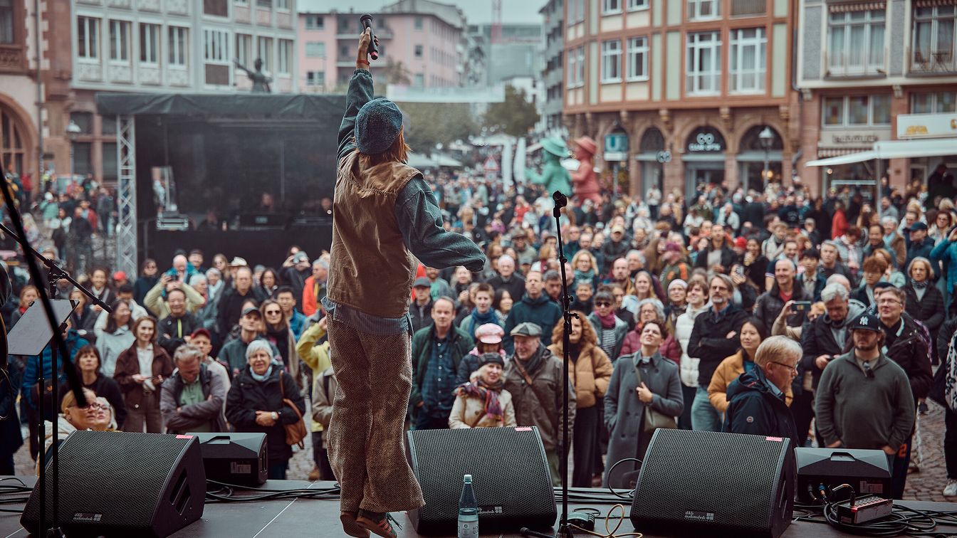 Performer on stage with microphone and crowd at Römerberg
