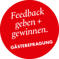 Roter Kreis mit Text „Feedback geben + gewinnen. Gästebefragung"