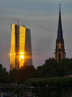 Sonnenuntergang spiegelt sich in der gläsernen Fassade eines Hochhauses in Frankfurt.