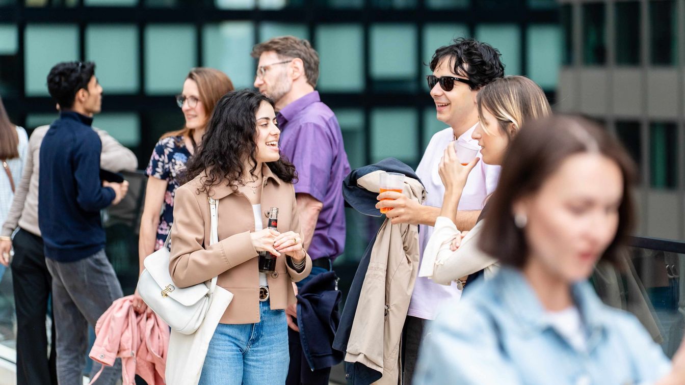 Menschen unterhalten sich bei einem Empfang vor moderner Glasfassade in Frankfurt.