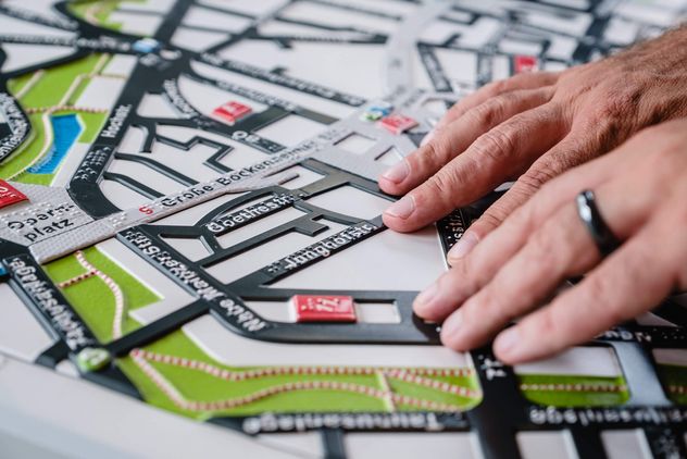 Hände auf einem Ausschnitt des Frankfurter Stadtplans mit Braille-Schrift.