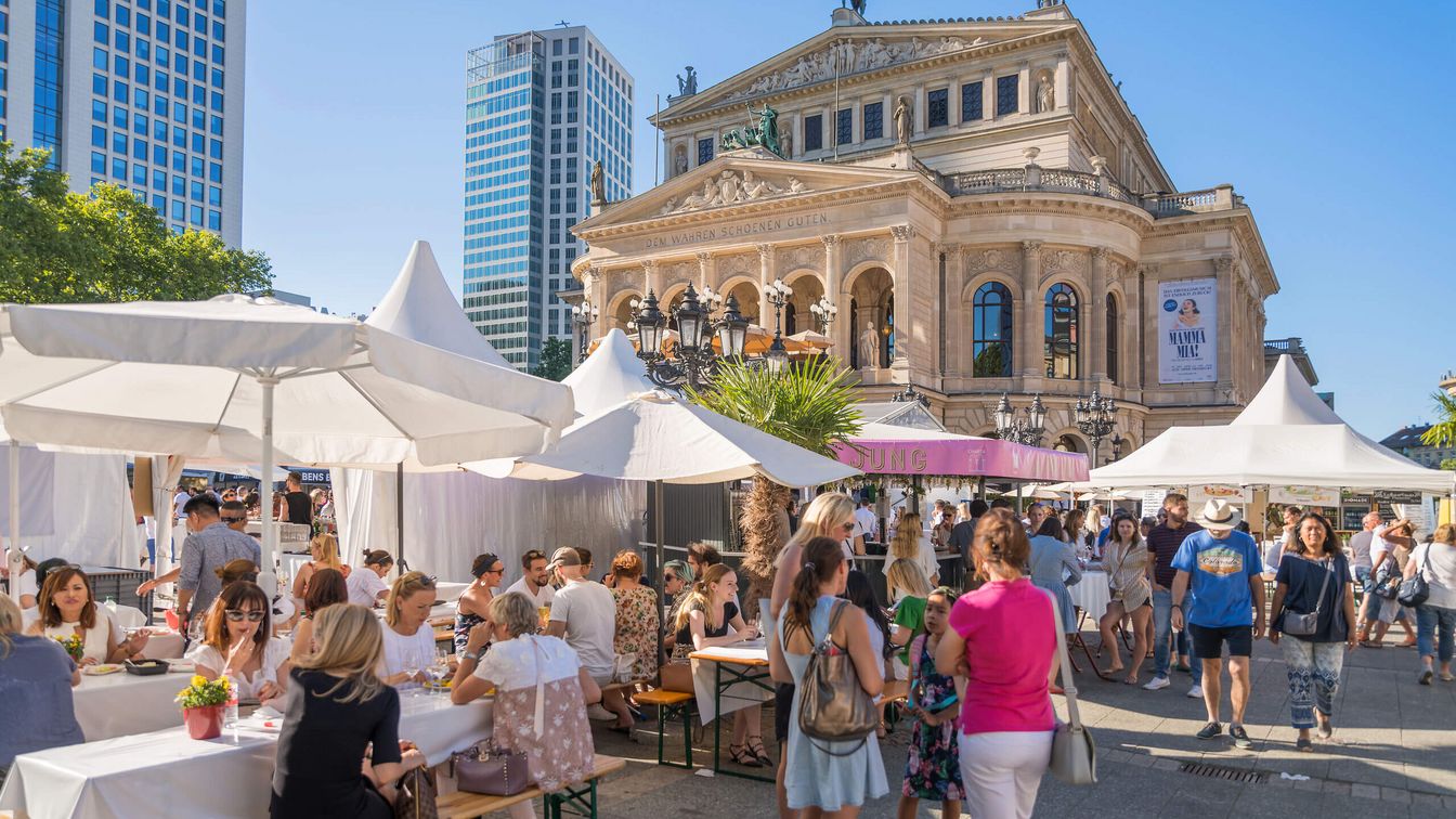 Menschen genießen das sommerliche Opernplatzfest vor der Alten Oper in Frankfurt. Zelte, Sitzbänke und Stände schaffen ein lebendiges Ambiente.