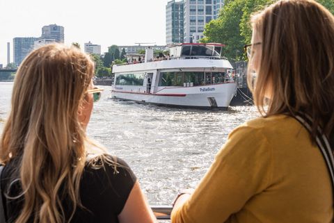 Zwei Frauen schauen während einer Schifffahrt auf ein andere Fahrgastschiff