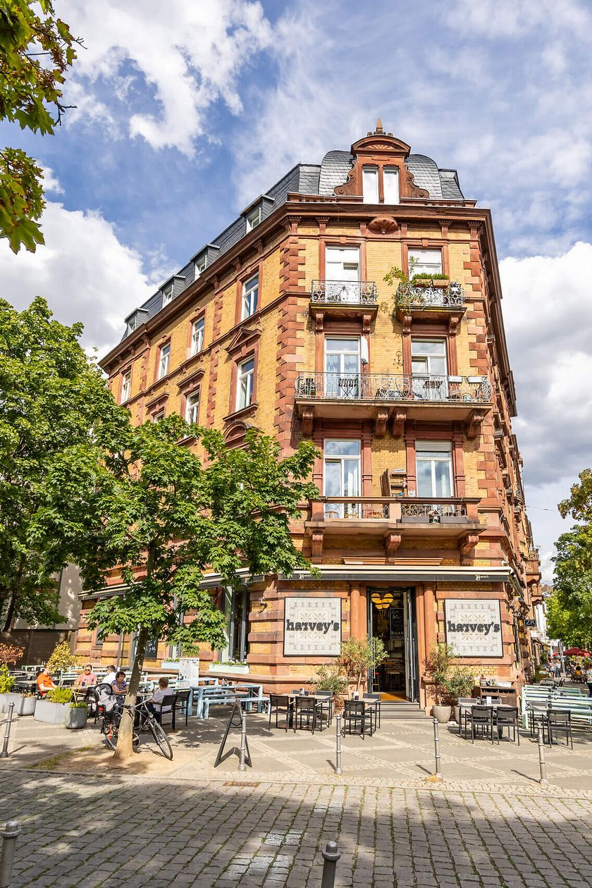 Blick auf ein historisches Gebäude in Frankfurt, Bäume und gepflasterter Platz.