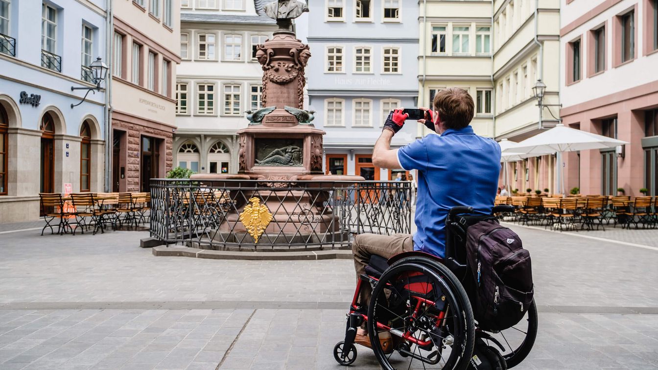 Man in wheelchair taking a photo of the Stoltze Fountain in the New Old Town.