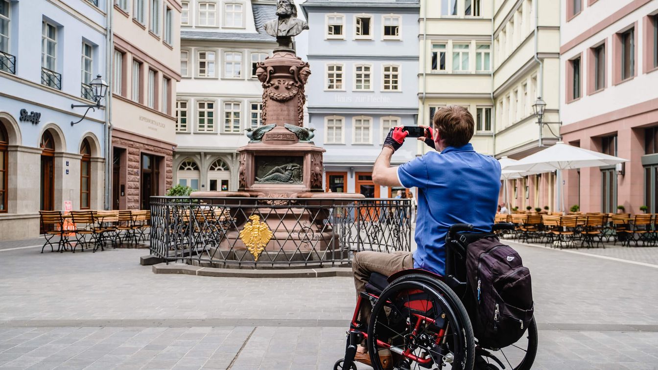 Rollstuhlfahrer fotografiert den Stoltze-Brunnen in der Neuen Altstadt.