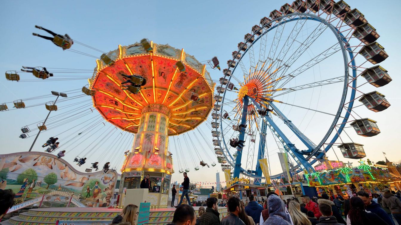 People stand below the chain carousel and the Ferris wheel during the Dippemess. 